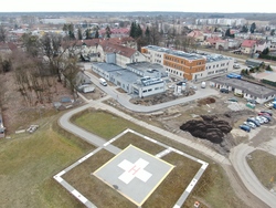 Opis. Na pierwszym planie lądowisko dla śmigłowców, na drugim powstający Szpitalny Oddział Ratunkowy oraz stara i nowa bryła szpitala.